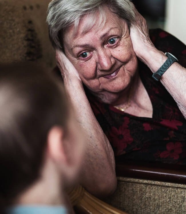 Two caregivers assisting elderly person at home
